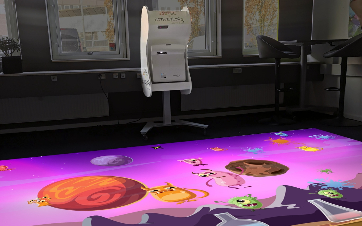 An ActiveFloor projector beams a colourful and interactive game onto the floor, inviting users to engage in playful exploration and movement, and enjoy an immersive educational experience. 